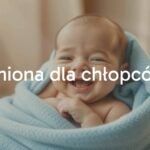 A happy newborn baby boy wrapped in a soft blue blanket, gentle sunlight, peaceful and warm atmosphere, realistic.